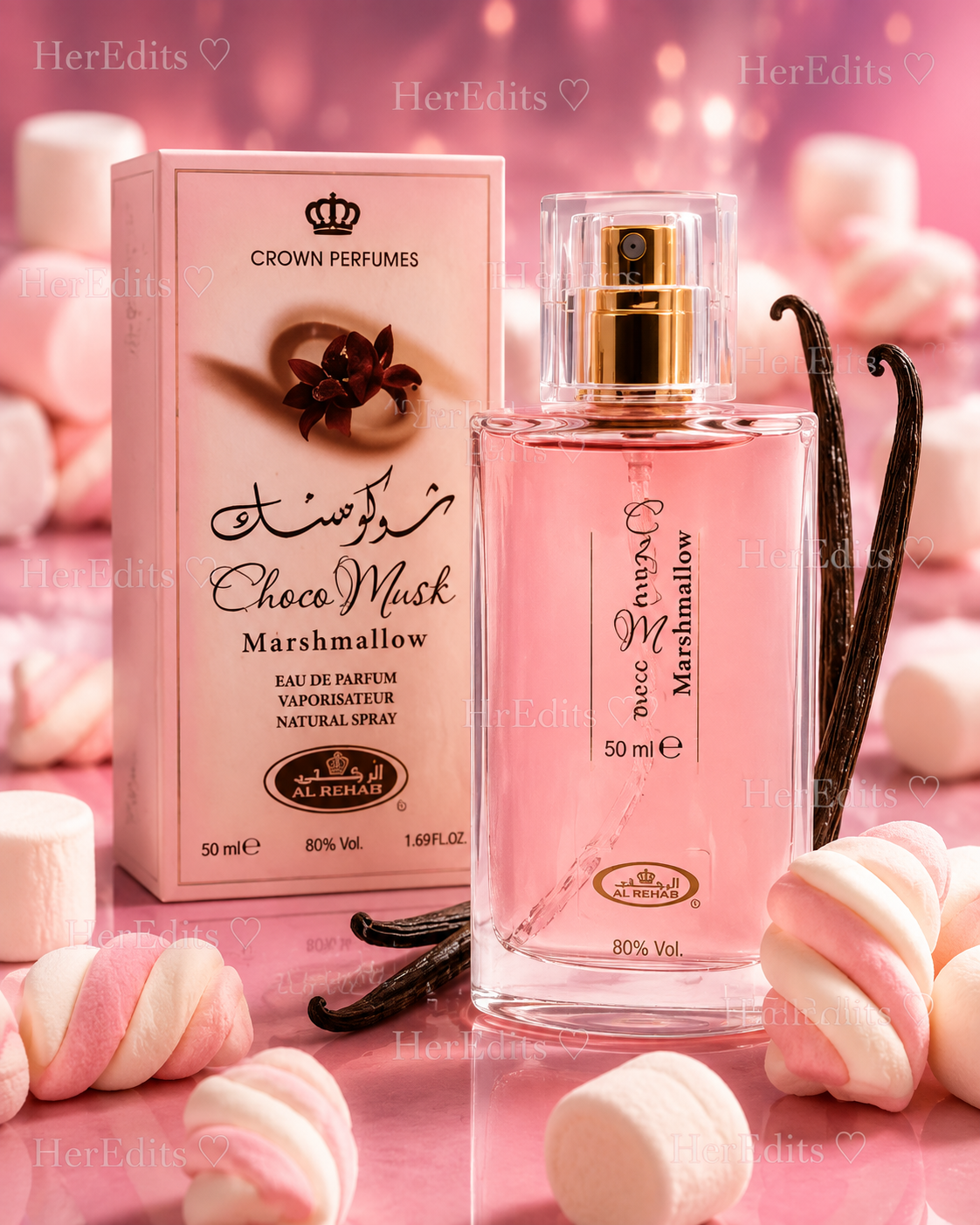 A bottle and box of Crown Perfumes 'Choco Musk' Marshmallow Eau de Parfum, styled with pink marshmallows and vanilla beans on a pink background.