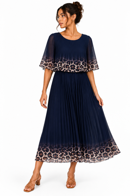 A woman modeling a navy blue midi dress with leopard print and ombre transition details on the sleeves and hem, paired with tan heeled sandals against a plain white background.