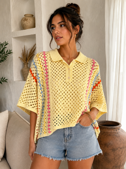 A woman wearing a yellow open-knit short-sleeve polo shirt with colorful striped accents, paired with denim shorts, standing in a bright, modern room.